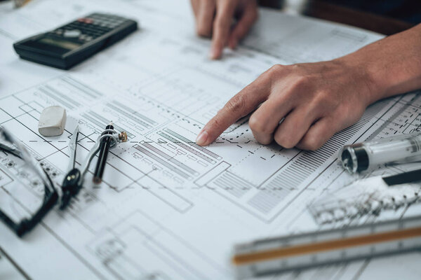 Engineering working with drawings inspection on the office desk and Calculator, triangle ruler, safety glasses, compass, vernier caliper on Blueprint. Engineer, Architect, Industry and factory concept.