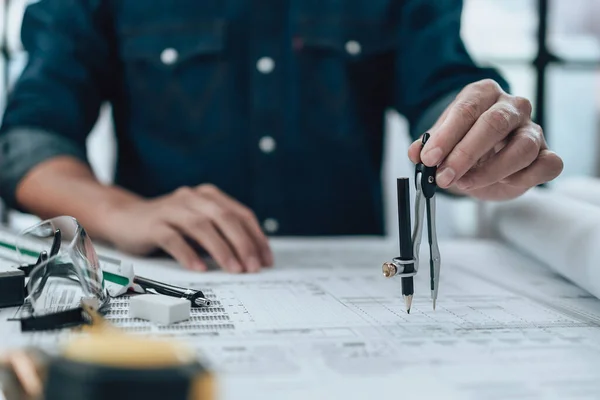 Engineering working with drawings inspection and writing on the office desk and Calculator, triangle ruler, safety glasses, compass, vernier caliper on Blueprint. Engineer, Architect, Industry and factory concept.