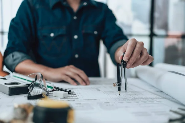 Engineering working with drawings inspection and writing on the office desk and Calculator, triangle ruler, safety glasses, compass, vernier caliper on Blueprint. Engineer, Architect, Industry and factory concept.