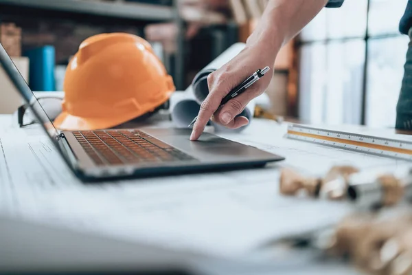 Engineering working with drawings inspection on laptop  in the office and Calculator, triangle ruler, safety glasses, compass, vernier caliper on Blueprint. Engineer, Architect, Industry and factory concept.