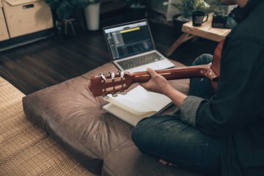 Genç adam evdeki oturma odasında kanepede otururken rahatlayıp gitar çalıyor. Müzik melodi, dizüstü bilgisayarda sözler ve pratik konsepti yaratır.