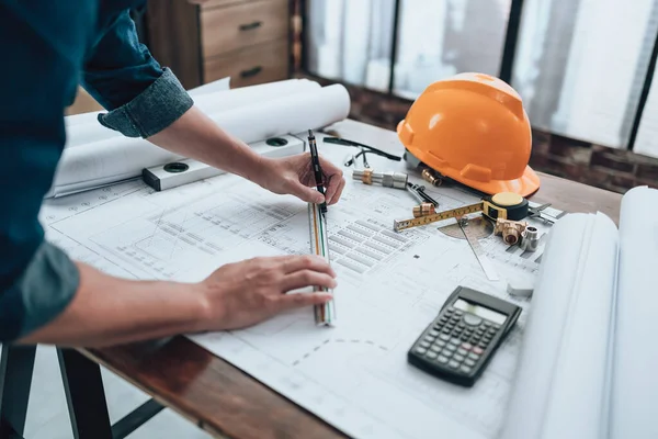 Engineering working with drawings inspection and writing on the office desk and Calculator, triangle ruler, safety glasses, compass, vernier caliper on Blueprint. Engineer, Architect, Industry and factory concept.