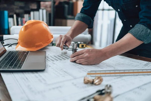 Engineering working with drawings inspection on the office desk and Calculator, triangle ruler, safety glasses, compass, vernier caliper on Blueprint. Engineer, Architect, Industry and factory concept.