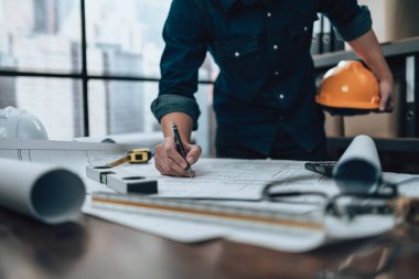 Mühendislik büro masası ve hesap makinesinde çizim teftişi, üçgen cetvel, güvenlik gözlükleri, pusula, planda daha düşük kalibre. Mühendis, Mimar, Endüstri ve Fabrika Konsepti.