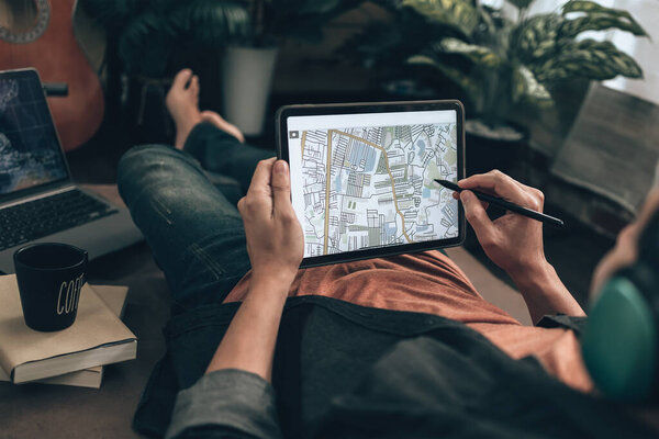 Путешественники планируют поездки и используют планшет для бронирования отелей, покупки авиабилетов, поиска карты, или найти маршруты путешествия на диван-кровать в гостиной у себя дома. Концепция путешествия.