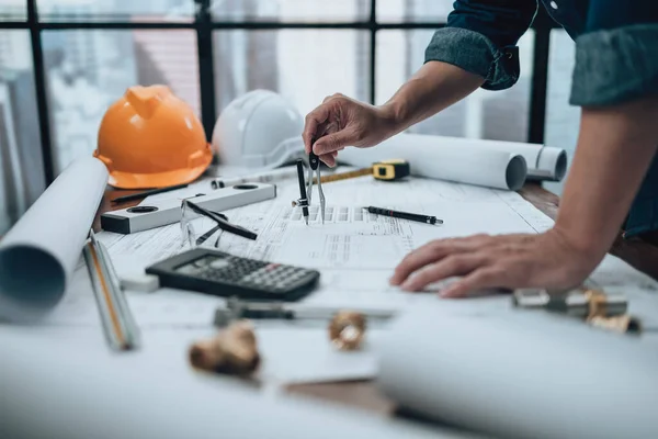 Engineering working with drawings inspection and writing on the office desk and Calculator, triangle ruler, safety glasses, compass, vernier caliper on Blueprint. Engineer, Architect, Industry and factory concept.