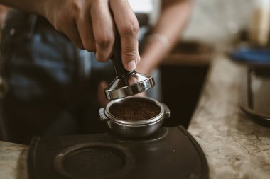 Barista, portafilter 'a kahve basmak için kurcalayıcı kullanıyor. Kahve makinesi konsepti
