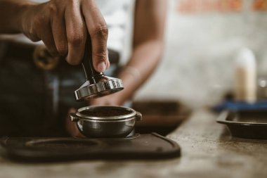 Barista, portafilter 'a kahve basmak için kurcalayıcı kullanıyor. Kahve makinesi konsepti