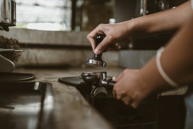 Barista, portafilter 'a kahve basmak için kurcalayıcı kullanıyor. Kahve makinesi konsepti
