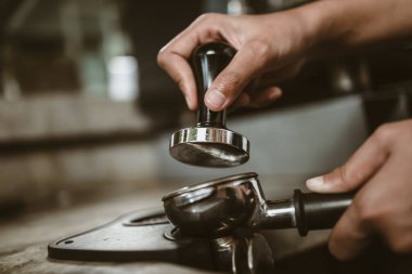 Barista, portafilter 'a kahve basmak için kurcalayıcı kullanıyor. Kahve makinesi konsepti