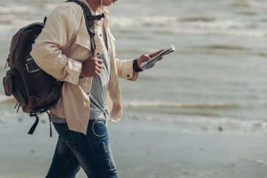 Turistler, eğlence yerleri, restoranlar ya da oteller bulmak için haritalar tutuyor ve sahilde yürüyorlar. Sırt çantası ve seyahat kavramı.