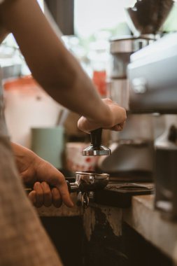 Barista, portafilter 'a kahve basmak için kurcalayıcı kullanıyor. Kahve makinesi konsepti