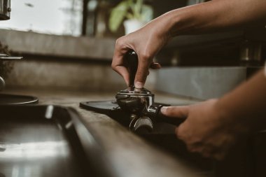 Barista, portafilter 'a kahve basmak için kurcalayıcı kullanıyor. Kahve makinesi konsepti