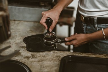 Barista, portafilter 'a kahve basmak için kurcalayıcı kullanıyor. Kahve makinesi konsepti