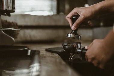 Barista, portafilter 'a kahve basmak için kurcalayıcı kullanıyor. Kahve makinesi konsepti