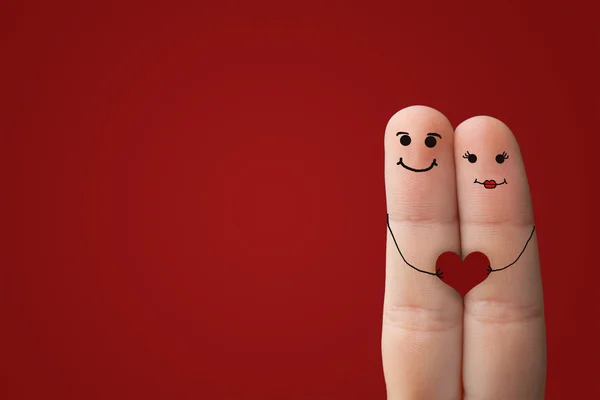 Casal feliz no amor com pintado sorridente segurando coração vermelho — Fotografia de Stock