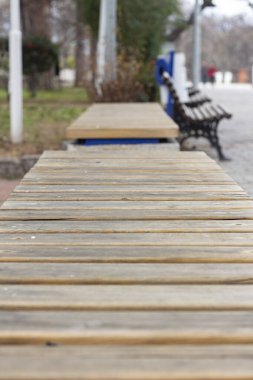 Şehir parkındaki ahşap bir bankın dikey görüntüsü. Parkta ahşap bir bank. Açık hava park bankları