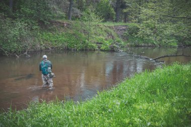 The fisherman catches with a spinning rod on the river.
