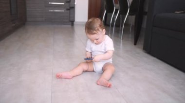 Küçük bebek yerde akıllı telefonla oynuyor.