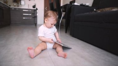 Meraklı çocuk yerde oturup tabletle oynuyor.