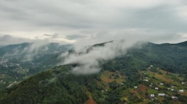 Aerial view of a village in the lush green rain cloud cover tropical rain forest mountain during the rainy season in Ukraine. High quality 4k footage
