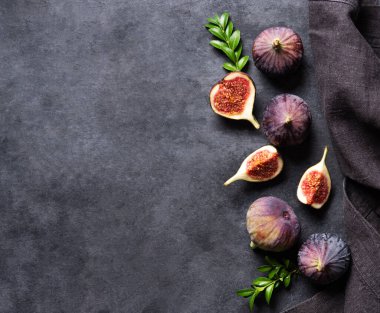 Taze incir, dilimler ve koyu gri arka planda peçete. Sağlıklı yemek kavramı. Boşluğu ve üst görünümü kopyala.