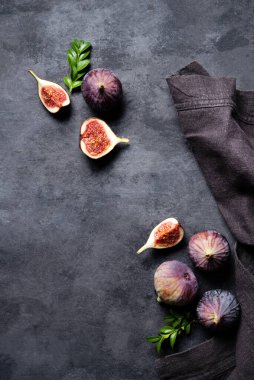 Taze incir, dilimler ve koyu gri arka planda peçete. Sağlıklı yemek kavramı. Boşluğu ve üst görünümü kopyala.