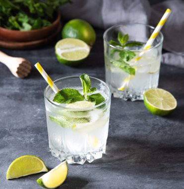 iki bardak limonata mojito, limon dilimleri ve gri arka planda nane şekeri. Karanlık fotoğraf. Makro ve resmi kapat