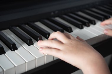  Bir kız eli elektronik piyano çalar. Çocuk aktivitelerini geliştirme kavramı. Yüzü olmadan ve resmi kapatmadan