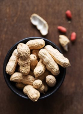 Siyah bir kasenin içindeki soyulmamış fıstıklar, siyah ahşap arka planda. Makro ve görüntüyü kapat. Üst görünüm.