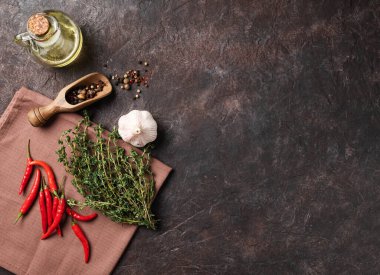 Baharatlar ve taze otlar, sarımsak, kırmızı biber ve koyu kahverengi arka planda yağ. Lezzetli ve sağlıklı yemek kavramı. Üst görünüm ve kopyalama alanı.