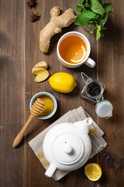 Bağışıklık sistemi güçlendirici. Koyu ahşap arka planda zencefil, bal, limon, nane ve baharatla bembeyaz çay. Sağlıklı içecek kavramı. Üst görünüm