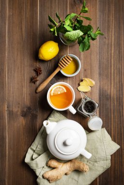 Bağışıklık sistemi güçlendirici. Koyu ahşap arka planda zencefil, bal, limon, nane ve baharatla bembeyaz çay. Sağlıklı gıda kavramı. Üst görünüm.