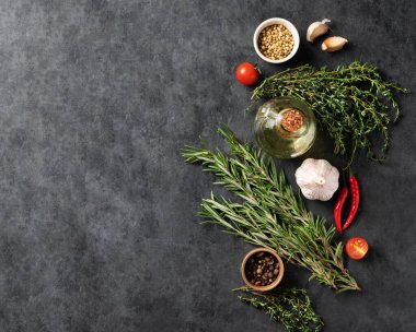 Baharatlar, baharatlar ve taze otlar, kekik, biberiye, kişniş, sarımsak, biber, domates biberi koyu gri arka planda. Lezzetli ve sağlıklı yemek kavramı. Üst görünüm ve kopyalama alanı.