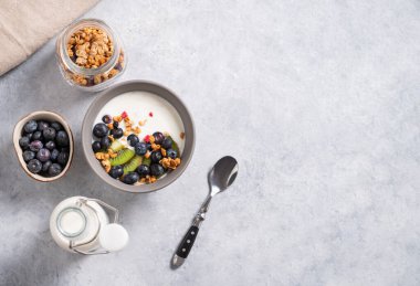 The concept of a healthy breakfast of vegetarian yogurt, granola and fresh fruit on a blue background. Top view and copy space.