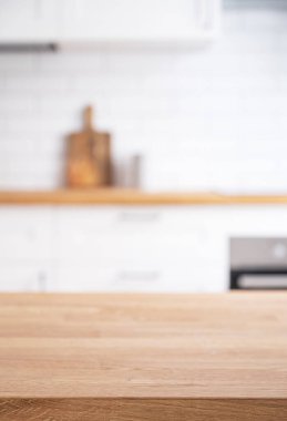 Wooden oak countertop with free space for mounting a product or layout against the background of a  blurred white kitchen.