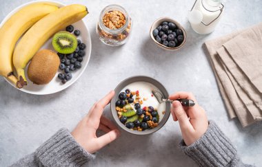the child has breakfast with a hearty and healthy yogurt with granola and fresh fruits and berries. Top view.