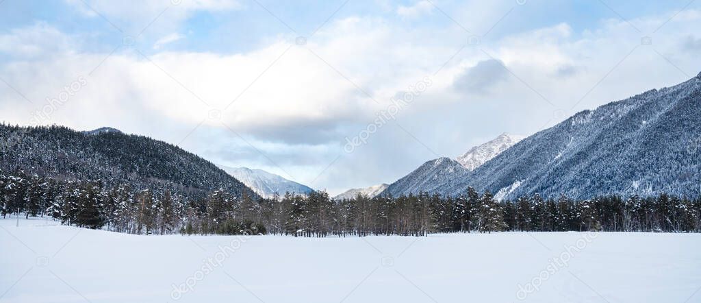 Beautiful landscape in Arkhyz with mountains, snow and forest on a cloudy winter day. Caucasus Mountains, Russia. Empty foreground.