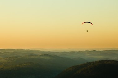 Moto paraglider above the landscape in sunset