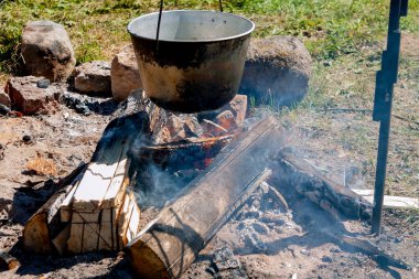Büyük bir tencere yanan ateşin üzerinde duruyor.