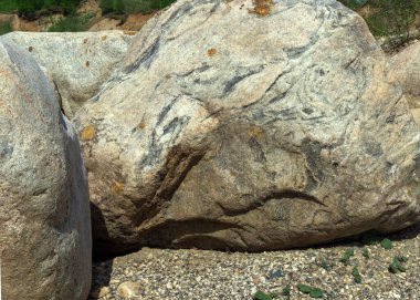 Kumun üzerinde birkaç büyük taş var. Ön planda büyük gri bir taş yatar. Taşın yapısında gri ve sarı gölgeler de var. Taş ocağında madencilik..