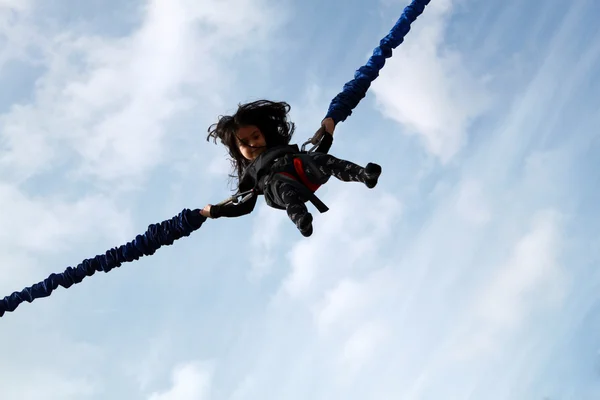 Kleines Mädchen springt auf Bungee auf blauem Himmel Hintergrund — Stockfoto