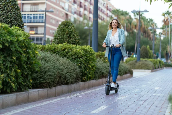 Content kobieta jazda skuter elektryczny w mieście — Zdjęcie stockowe