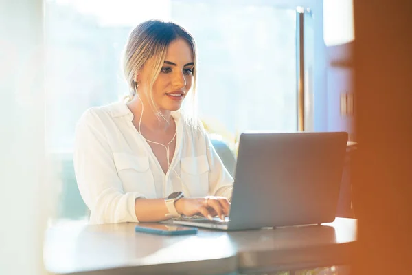 Mujer de negocios contenido escribiendo en el ordenador portátil en la cafetería — Foto de Stock