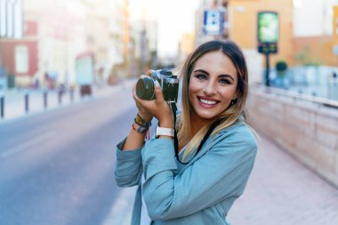 Şehirde geçmişe dönük kamerası olan pozitif fotoğrafçı