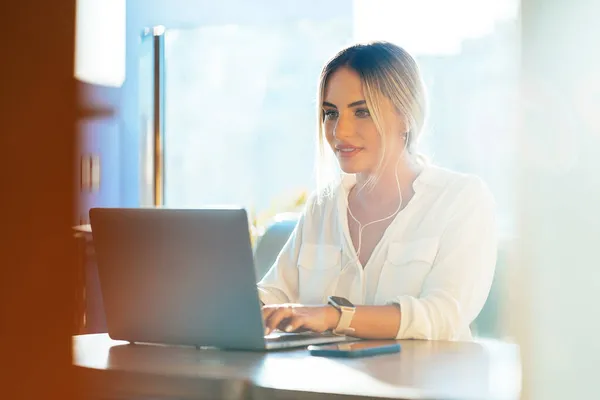 Elegante mujer de negocios escribiendo en el ordenador portátil en la cafetería — Foto de Stock