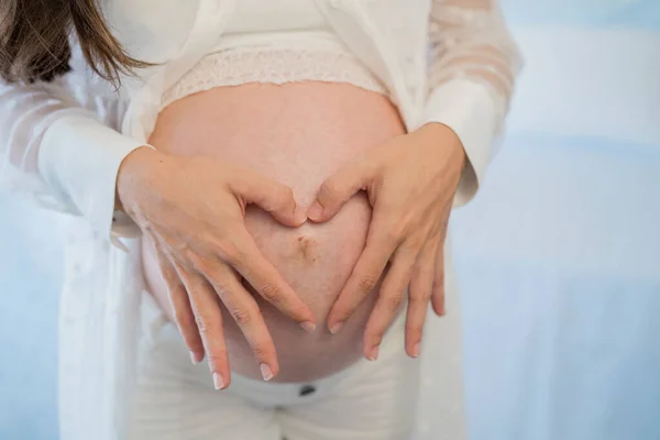 Беременная женщина нежно трогает живот в комнате. — стоковое фото