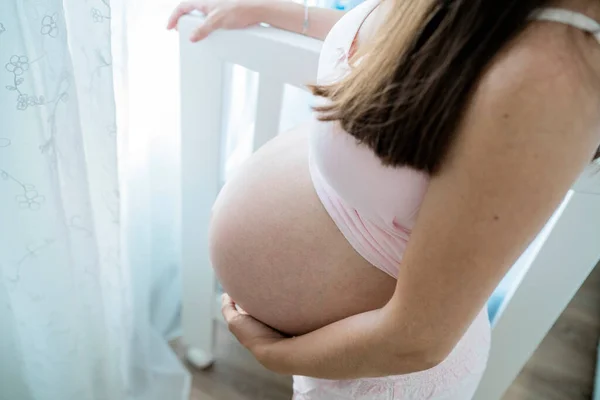 Unerkennbare Schwangere berührt Bauch im Babyzimmer — Stockfoto