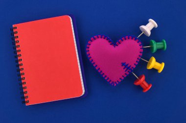Kalp ağrısı, çeşitli renklerde iğne batırılmış tıbbi konsept keçeli kalbe saplanmış acı yoğunluğunu sembolize eden açık tele bağlı not defteri.
