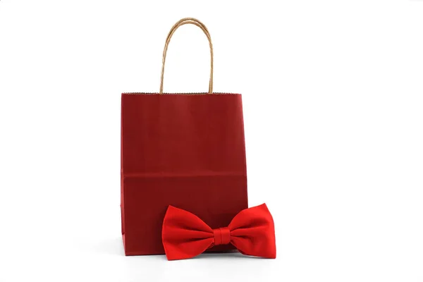 白い背景に赤い蝶ネクタイの赤い紙のショッピングバッグ 紳士やショッピングのコンセプトへの贈り物 — ストック写真
